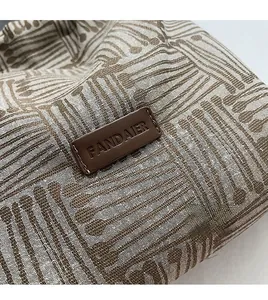 Detailed view of the woven canvas texture and leather logo label on the tote bag