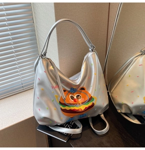 Detail of silver metallic tote bag featuring cartoon hamburger bear print and top handle