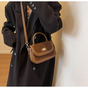 Detail of vintage caramel brown leather bag with suede patchwork on a black coat