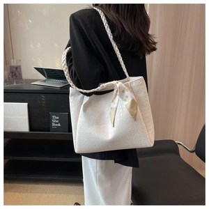 Close-up of white tote bag featuring embossed textures and woven leather shoulder straps
