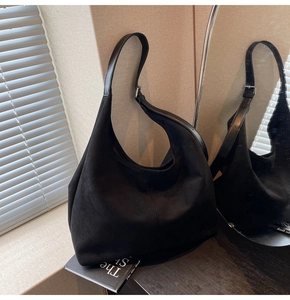 Close-up of black suede hobo bag featuring matte texture and silver metal buckle
