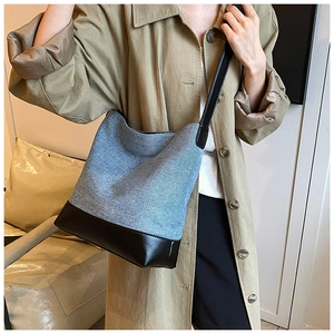Detail of blue denim bucket bag with black leather patchwork and sleek shoulder strap