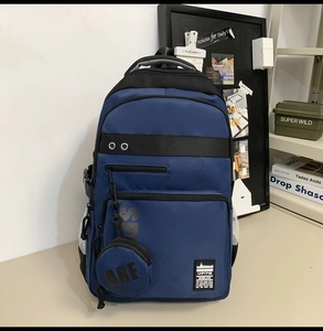 Detail view of navy blue backpack with front zipper pockets and circular coin purse charm