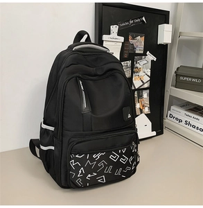 Close-up of durable black nylon backpack with white geometric lettering and side pockets
