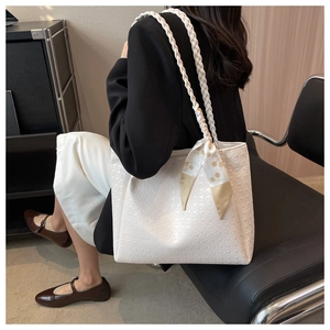 Detail of white tote bag featuring textured embossing and a decorative printed silk scarf