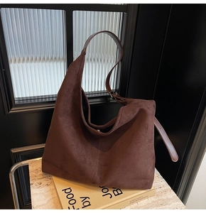 Detail of dark brown suede hobo bag showing its soft texture and decorative stitching
