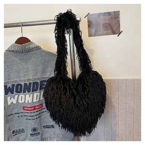 Détail d'un sac à bandoulière noir en forme de cœur avec plumes synthétiques sur support
