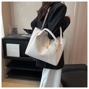 Detailed view of cream tote bag with embossed texture and woven handle featuring a silk scarf