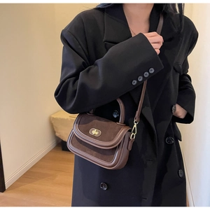 Detail of vintage dark brown crossbody bag with gold twist lock on black blazer