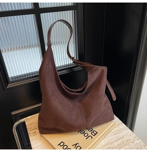 Macro view of stitching detail and adjustable strap on dark brown suede hobo bag