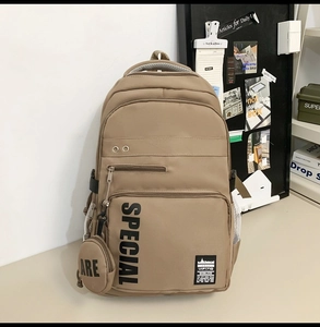 Detail view of khaki nylon backpack featuring front pockets and a detachable round coin purse