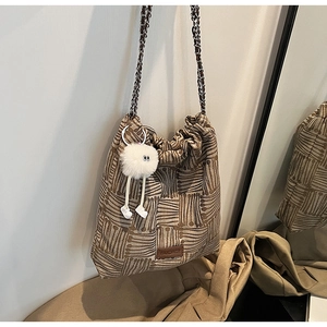 Detail of the brown canvas bucket bag showing geometric texture and silver chain strap