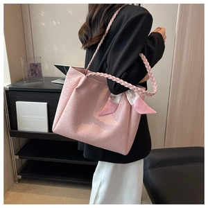 Detail of pink tote bag with embossed texture and woven rope handle with silk scarf