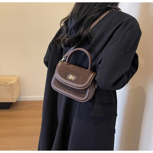Detail of a brown patchwork crossbody bag featuring suede textures and a gold metal lock
