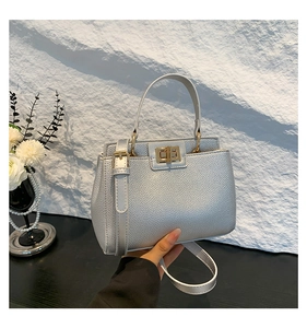 Detail of silver pebble grain leather handbag with gold twist lock and top handle