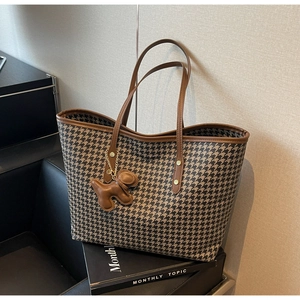 Detail of houndstooth tote bag with leather trim and decorative puppy charm