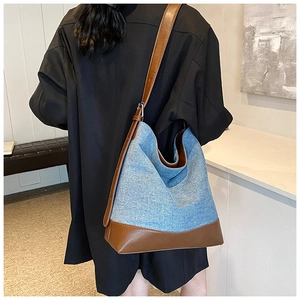 Detail of blue denim and brown leather contrast stitching on the large bucket bag
