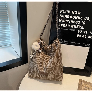 Close-up of striped canvas bucket bag with metal chain strap and plush pendant