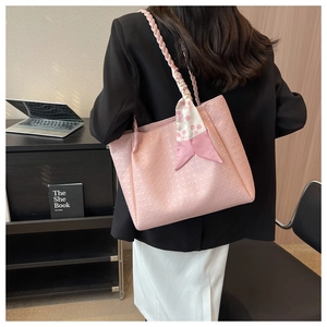 Detailed view of pink tote bag with checkered texture and decorative handle scarf