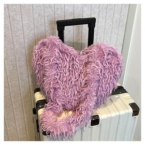 Gros plan d'un sac bandoulière en fausse fourrure violette en forme de cœur sur valise