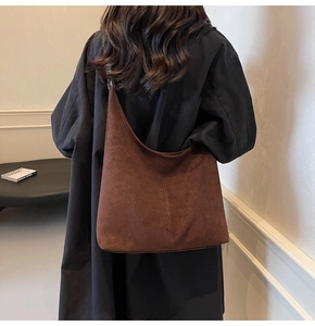 Model view of a large dark brown suede tote bag styled with a minimalist black coat