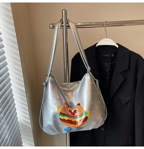 Detail view of silver tote bag featuring cartoon burger graphics and stylish long straps