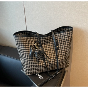 Close-up of houndstooth tote bag with leather trim and a cute puppy-shaped bag charm