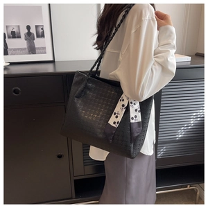 Detail of black houndstooth tote bag with woven handles and decorative floral silk scarf