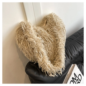 Détail du sac à main cœur en fausse fourrure beige posé sur un canapé en cuir noir