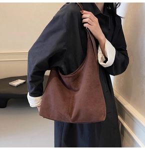 Detail of a large brown suede bucket bag with a minimalist vintage shoulder strap