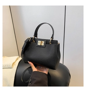 Detail of vintage black pebble leather handbag with gold twist lock and metal handle rings