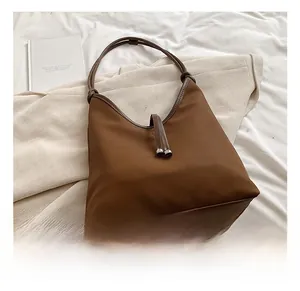 Close-up of brown suede shoulder bag with dual handles and silver metallic bead accents