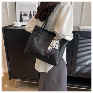 Detail of black tote bag with textured relief pattern and stylish side printed scarf