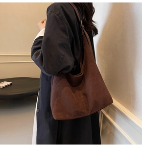 Brown faux suede tote bag shown on shoulder over a black coat for size reference