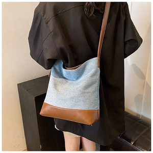 Detail of vintage denim bucket bag featuring contrast leather strap and polished finish
