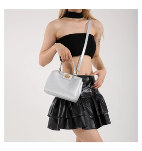 Silver textured handbag with gold twist lock shown styled on a black leather outfit