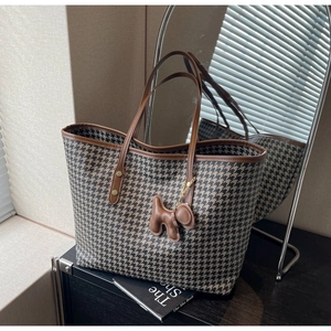 Detail of houndstooth tote bag with brown leather trim and cute puppy charm