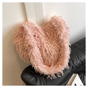 Gros plan du sac à bandoulière en plumes roses sur un canapé en cuir noir