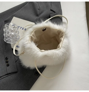 Detail view of white fluffy faux fur handbag with magnetic snap and thin leather strap