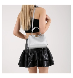 Detail of silver pebble textured handbag with golden twist lock and round handle