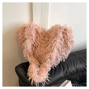 Détail du sac à main en fausse fourrure rose en forme de cœur sur canapé noir