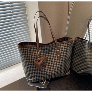 Detail of retro houndstooth tote bag with brown leather trim and cute puppy charm
