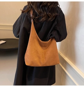 Detail of the brown suede bucket bag with fine stitching on a black coat backdrop
