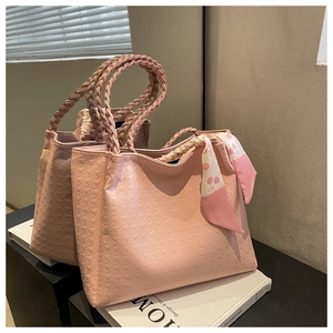 Pink textured leather tote bag detail with woven handles and cherry pattern scarf