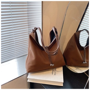 Detailed shot of brown nylon shoulder bag with leather knotted handles and silver ball charms