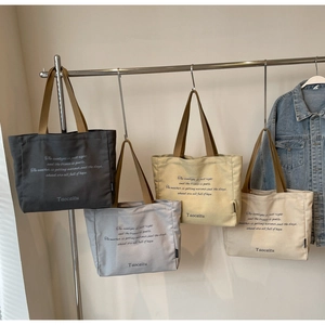 Detailed row of large capacity canvas tote bags in grey, blue, yellow and beige colors