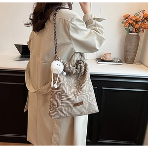Detail of canvas tote bag featuring retro stripes, chain strap and plush monster charm