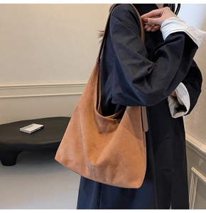 Close-up of brown suede hobo bag shown on shoulder, focusing on soft matte texture