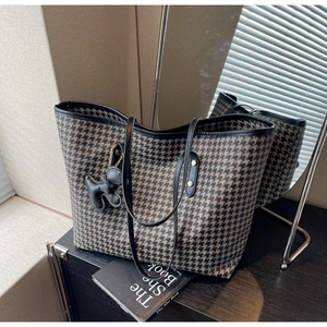 Close-up of houndstooth tote bag with black puppy charm and thin shoulder straps
