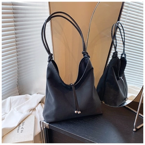 Detail of black tote bag with silver beads decoration on a reflective surface